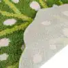Grön badrumsmatta med bladformad design och vit textur, närbild på baksidan.