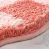 Blomformad rosa badrumsmatta med mjuk fluffig textur och färgglad gradient.