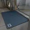 Blå badrumsmatta i diatomit, 90 cm, med vit logotyp vid hörnet.