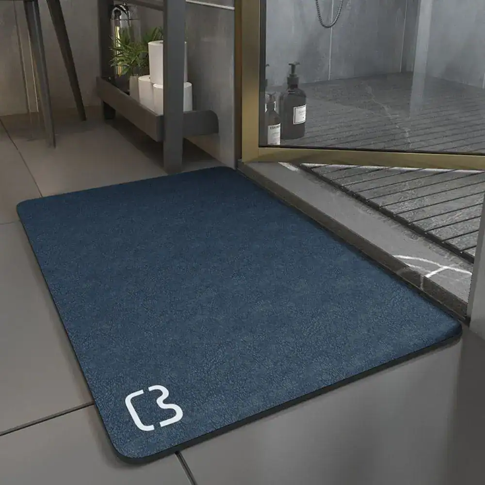Blå badrumsmatta i diatomit, 90 cm, med vit logotyp vid hörnet.