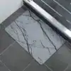 Badrumsmatta Diatomit Marmor Vit med svarta marmormönster på grå bakgrund.