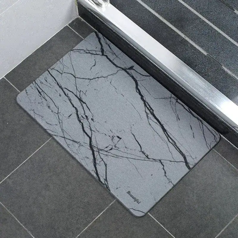 Badrumsmatta Diatomit Marmor Vit med svarta marmormönster på grå bakgrund.