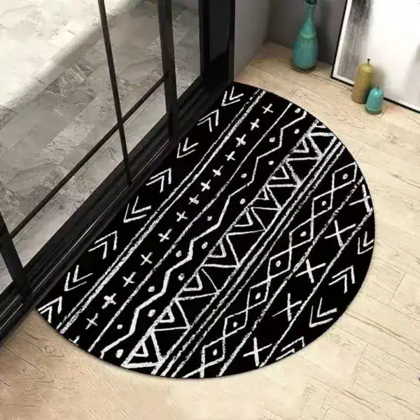 Svart halvmåneformad badrumsmatta med vit geometrisk mönster.