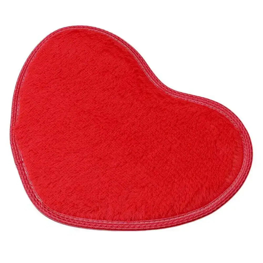 Röd hjärtformad badrumsmatta med mjuk textil yta och rundad kant.