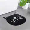 Svart kattformad badrumsmatta med vita detaljer, idealisk för badrummet.
