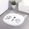 Vit badrumsmatta i kattform med svarta drag, mjuk och dekorativ för badrummet.