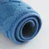 Blå mikrofiber badrumsmatta, mjuk och vattentät, rullad upp för visning.