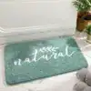 Badrumsmatta i naturlig grön färg med texten 'natural' i vit skrift, placerad vid badkar.