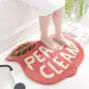 Badrumsmatta Peachy Clean i rosa, med text och bladmotiv, idealisk för badrum.