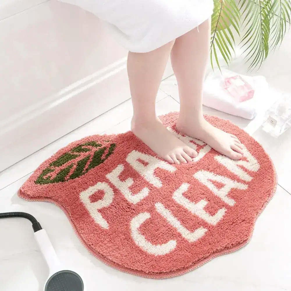 Badrumsmatta Peachy Clean i rosa, med text och bladmotiv, idealisk för badrum.