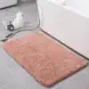 Badrumsmatta i taupefärg, mjuk och fluffig, placerad vid badkar med grå kakelbakgrund.