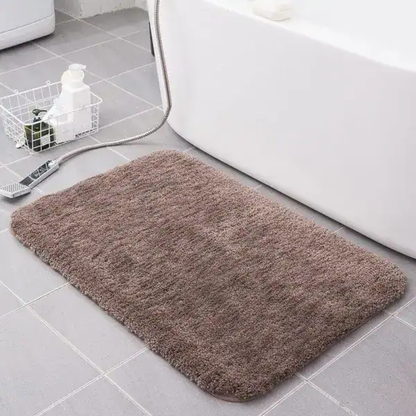 Badrumsmatta i taupe, mjuk och fluffig, idealisk för badrummet med badkar och grå kakel.
