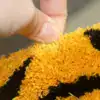Tigerformad badrumsmatta i orange och svart, närbild på textilens mjuka struktur.