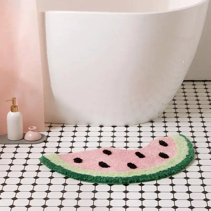 Badrumsmatta i vattenmelonform med rosa och grön färg, placerad vid en vit badkar.