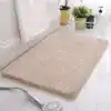Beige badrumsmatta med mjuk pälsliknande yta, placerad vid badkar och dusch.