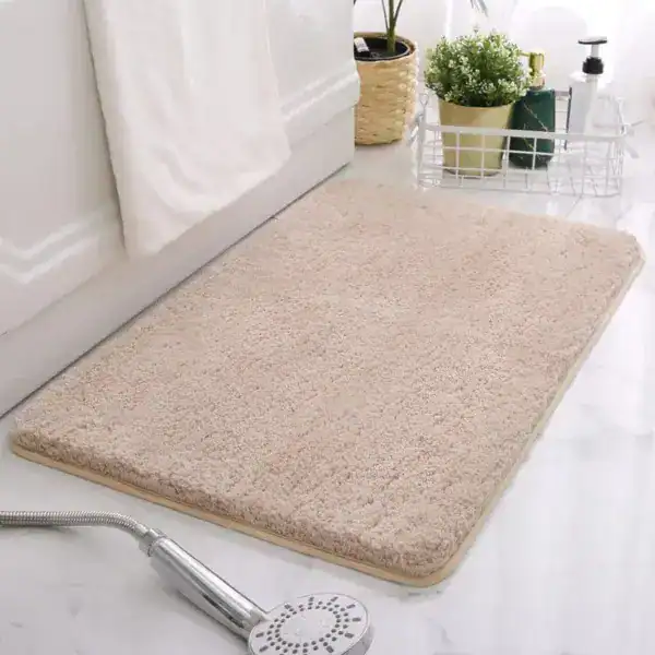Beige badrumsmatta med mjuk pälsliknande yta, placerad vid badkar och dusch.