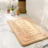 Beige badrumsmatta med präglat 'HOME'-motiv, idealisk för badrummet.