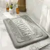 Beige badrumsmatta med präglat 'HOME'-motiv, idealisk för badrummet.
