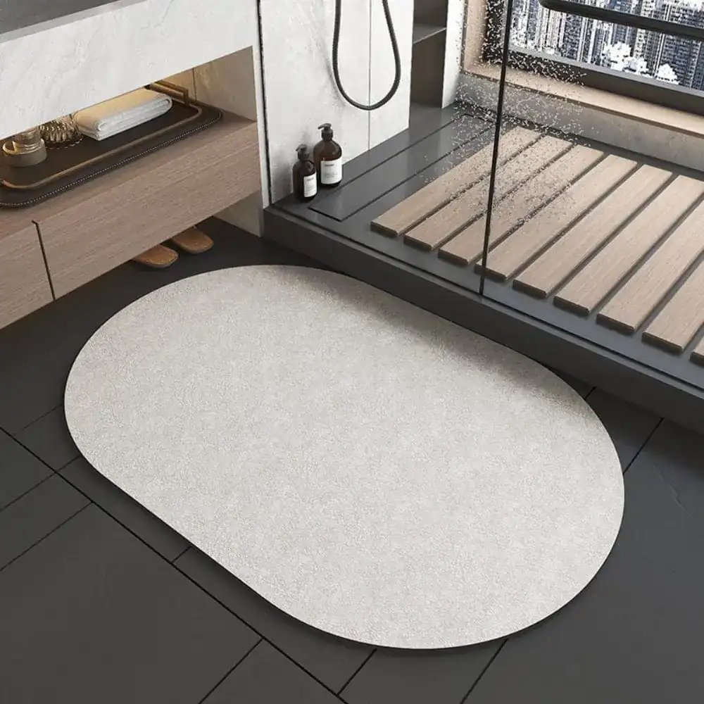 Oval grå duschmatta i badrum med modern design och mjuk textur.