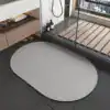 Oval grå duschmatta i badrummet, modern design, vattentät och slipad.