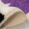 Färgglad badrumsmatta med prickmönster i lila, vit och svart, mjuk fluffig yta och texturerad botten.