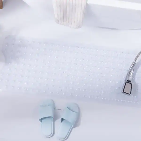 Transparent halkskydd för badkar med antiskridande textur och blå badslipper.