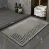 Grå duschmatta med gummikant och vattensänkor för badrum, modern design.