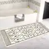 Lång badrumsmatta med boho-mönster i svart och vit, placerad framför badkar.