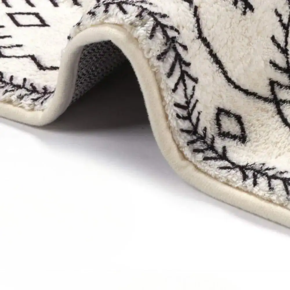 Lång badrumsmatta i boho-stil med svart-vit geometriskt mönster och mjuk textil.