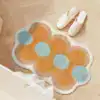 Orange badrumsmatta med blommig prickmönster i blått och beige på trägolv.