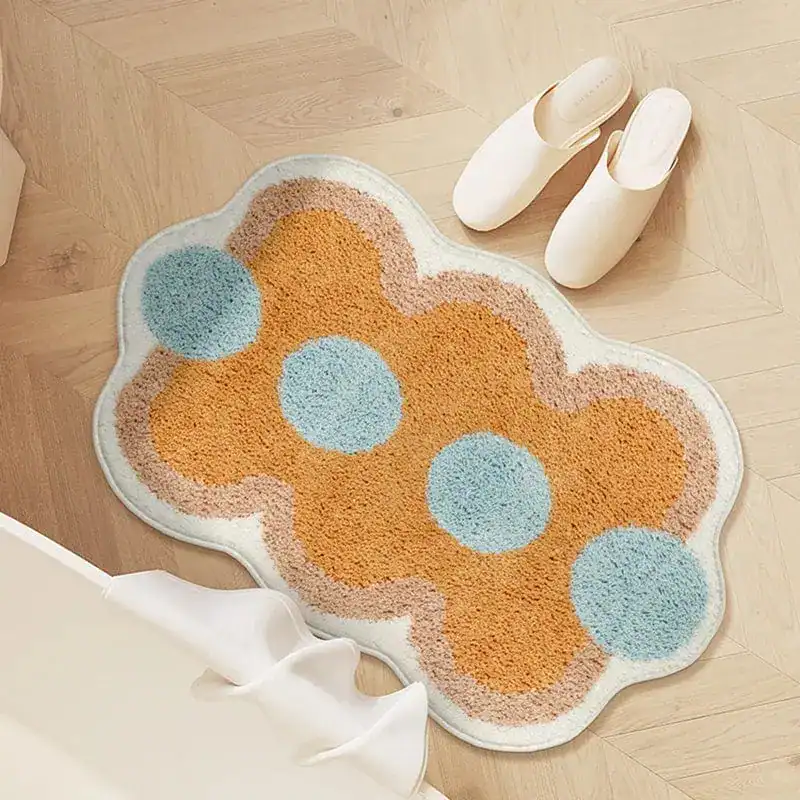 Orange badrumsmatta med blommig prickmönster i blått och beige på trägolv.