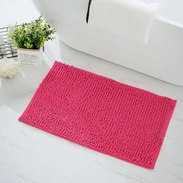Fuchsia badrumsmatta i mjuk fluffig textil, idealisk för badrummet med vit badkar och grön växt.