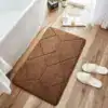 Brun kviltad badrumsmatta med geometrisk mönster vid badkar.