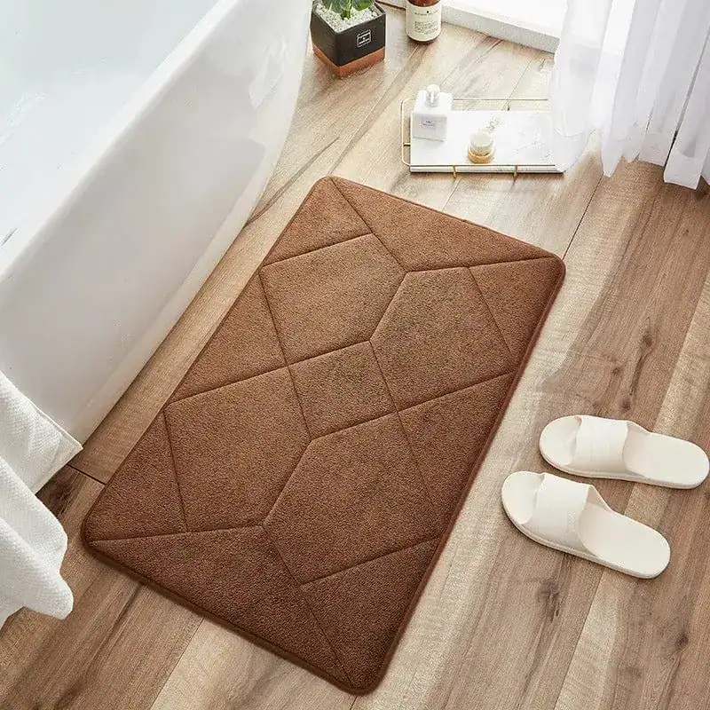 Brun kviltad badrumsmatta med geometrisk mönster vid badkar.