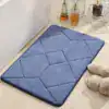 Blå kviltad badrumsmatta med geometrisk mönster vid badkar, idealisk för badrummet.