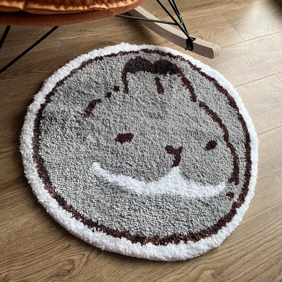 Rund badrumsmatta med kattmotiv i grått och brunt, mjuk och rundad design.