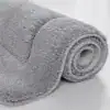 Stor badrumsmatta i grått, mjuk fluffig textil, rullad upp, idealisk för badrummet.