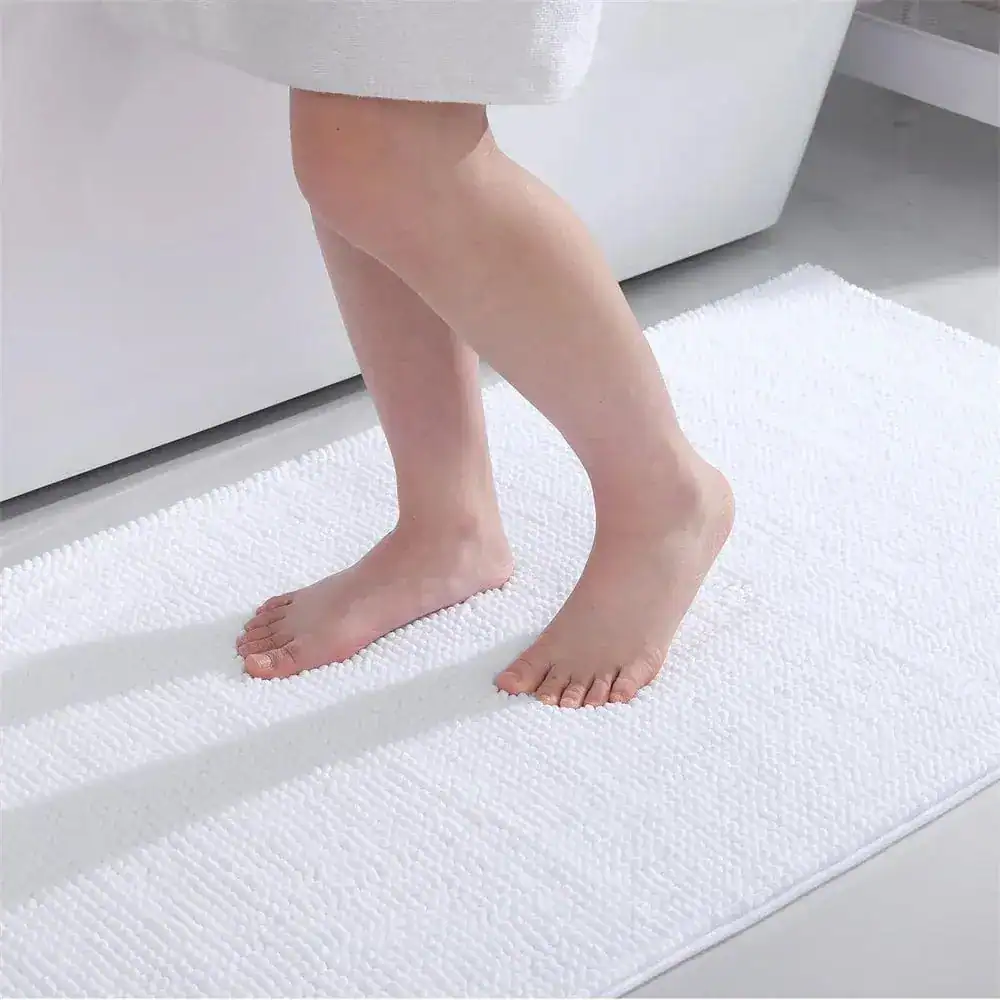 Vit badrumsmatta med texturerad yta, fot på mattan vid badkar.