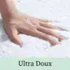 Händer som rör sig i en mjuk, vit badrumsmatta med Ultra Doux textur.