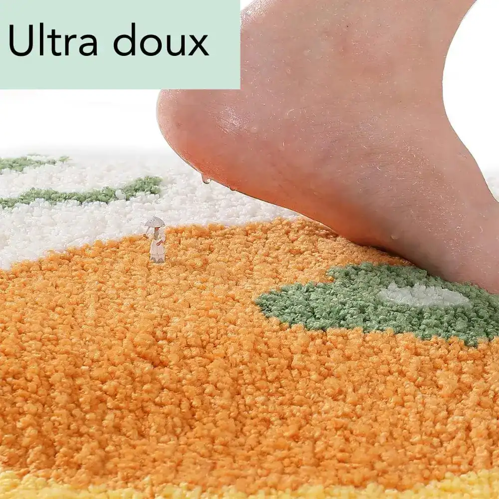 Orange badrumsmatta i fruktform med mjuk textur och grön bladdekoration.
